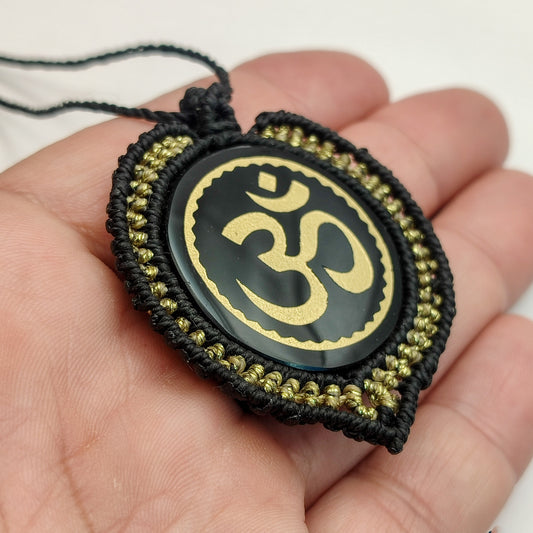 Primer plano del grabado dorado del mantra Om sobre espejo de obsidiana.