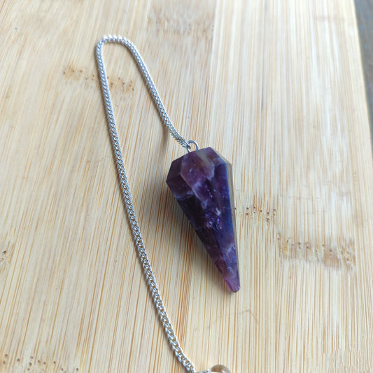 Péndulo esotérico de amatista colgado mostrando sus tonos morados y su equilibrio.