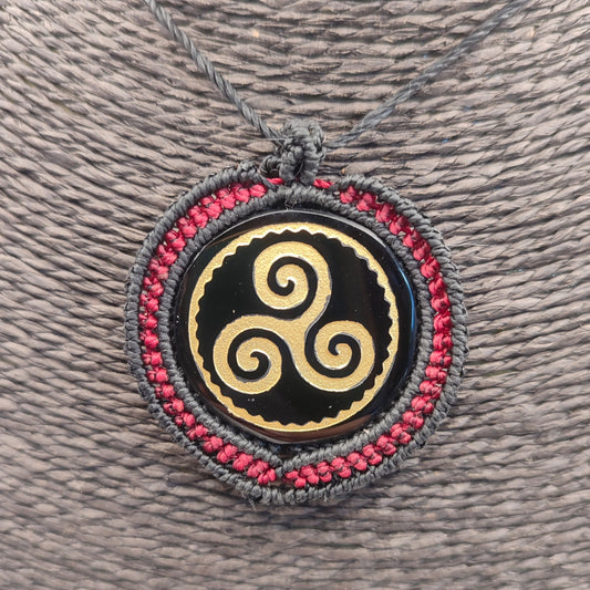 Primer plano del grabado dorado del Trisquel sobre espejo de obsidiana negra