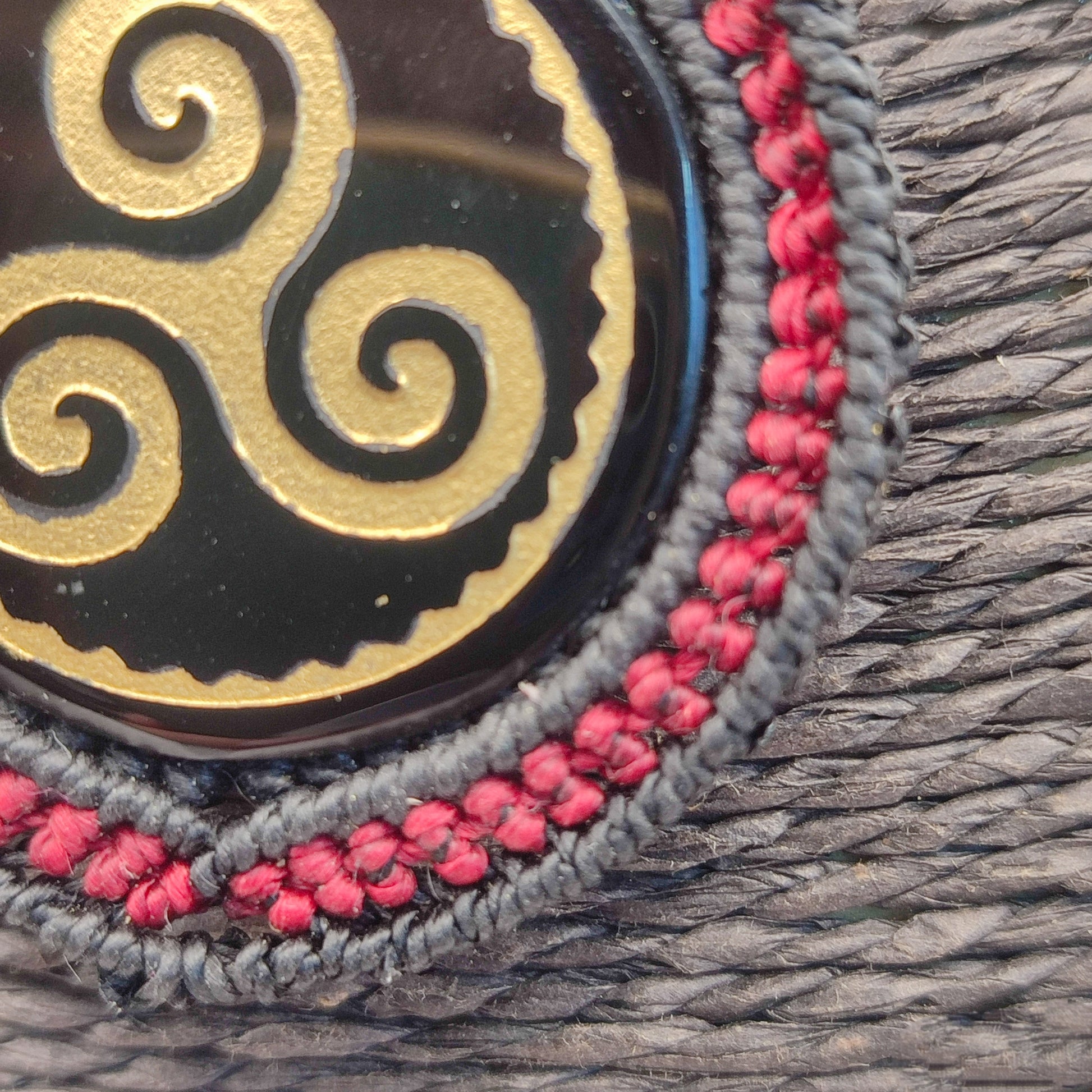 Vista detallada del tejido en rojo burdeos y negro envolviendo la obsidiana.