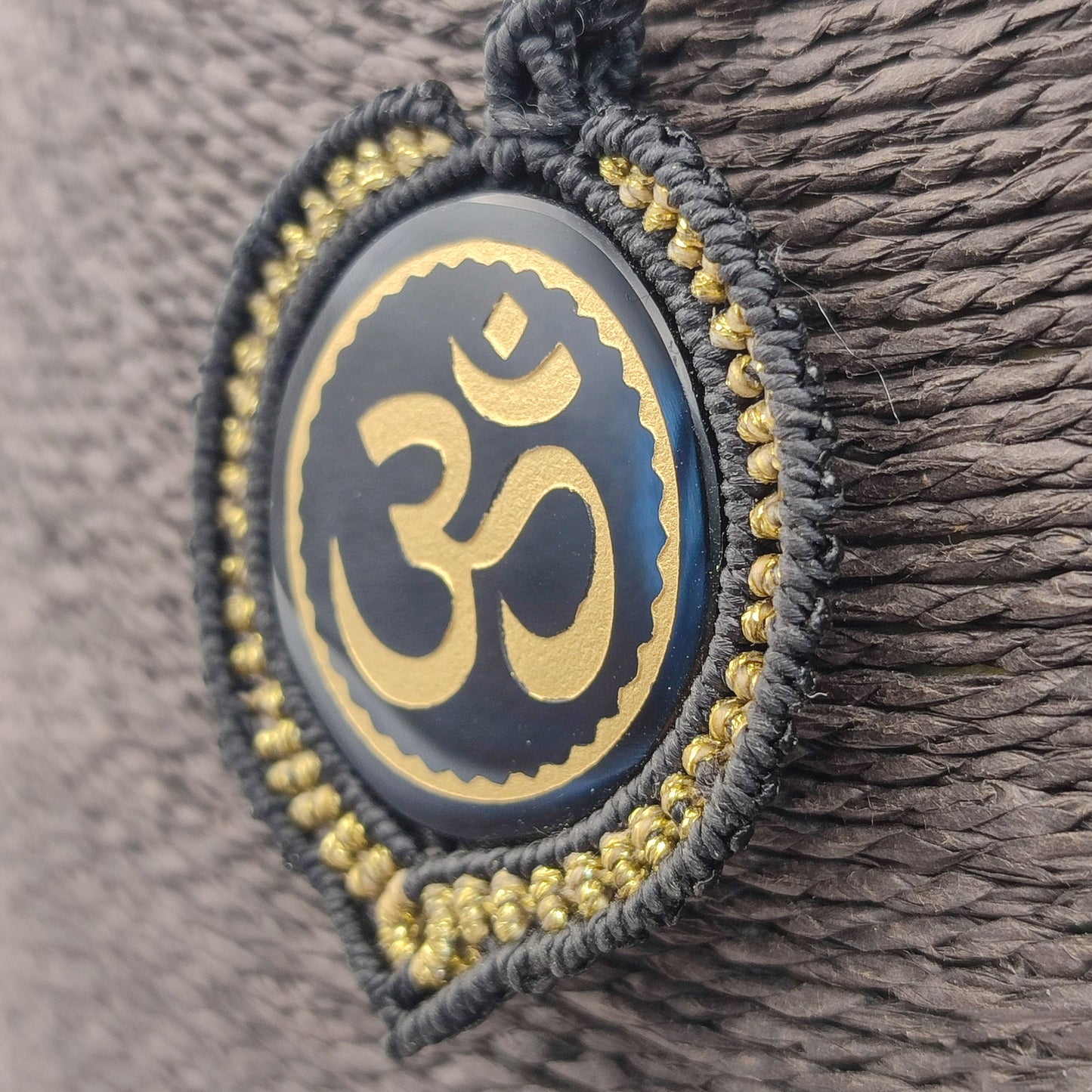 Vista lateral del tejido artesanal en negro y oro rodeando la piedra sagrada.