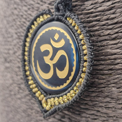 Vista lateral del tejido artesanal en negro y oro rodeando la piedra sagrada.