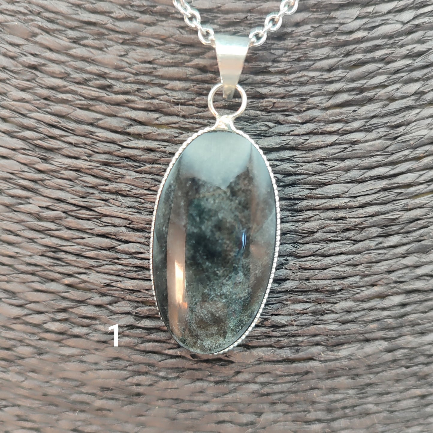 colgante artesanal de piedra obsidiana plateada natural con forma ovalada, engarzado en alpaca con baño de plata hecho a mano