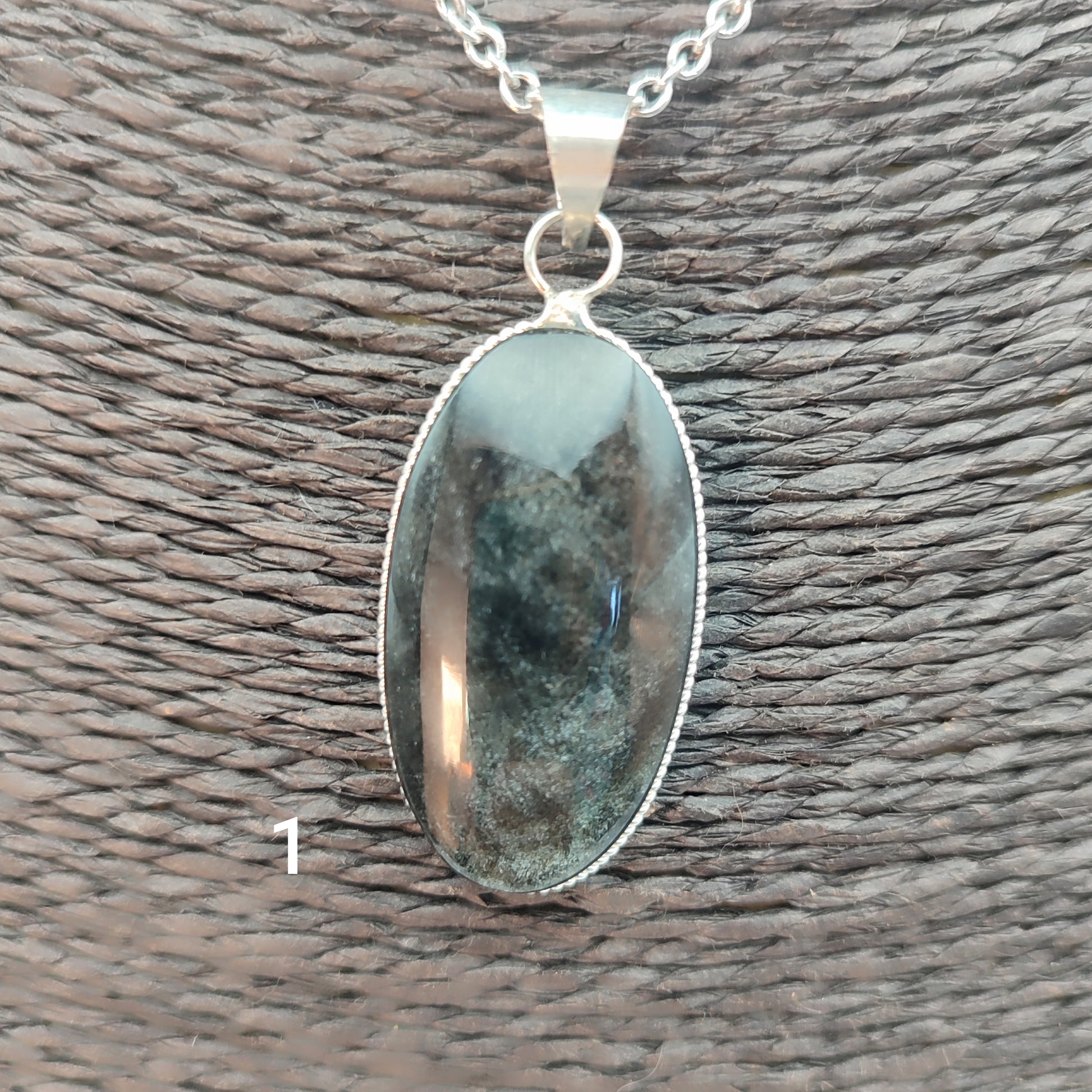 colgante artesanal de piedra obsidiana plateada natural con forma ovalada, engarzado en alpaca con baño de plata hecho a mano