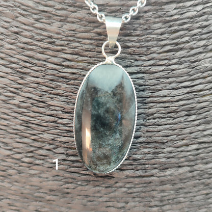 colgante artesanal de piedra obsidiana plateada natural con forma ovalada, engarzado en alpaca con baño de plata hecho a mano