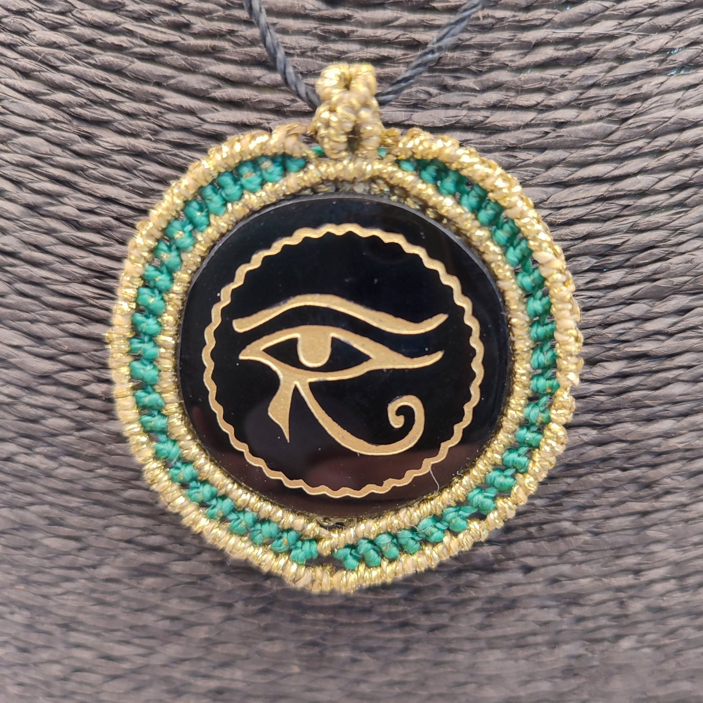 Colgante de obsidiana negra con grabado dorado del Ojo de Horus y macramé turquesa.
