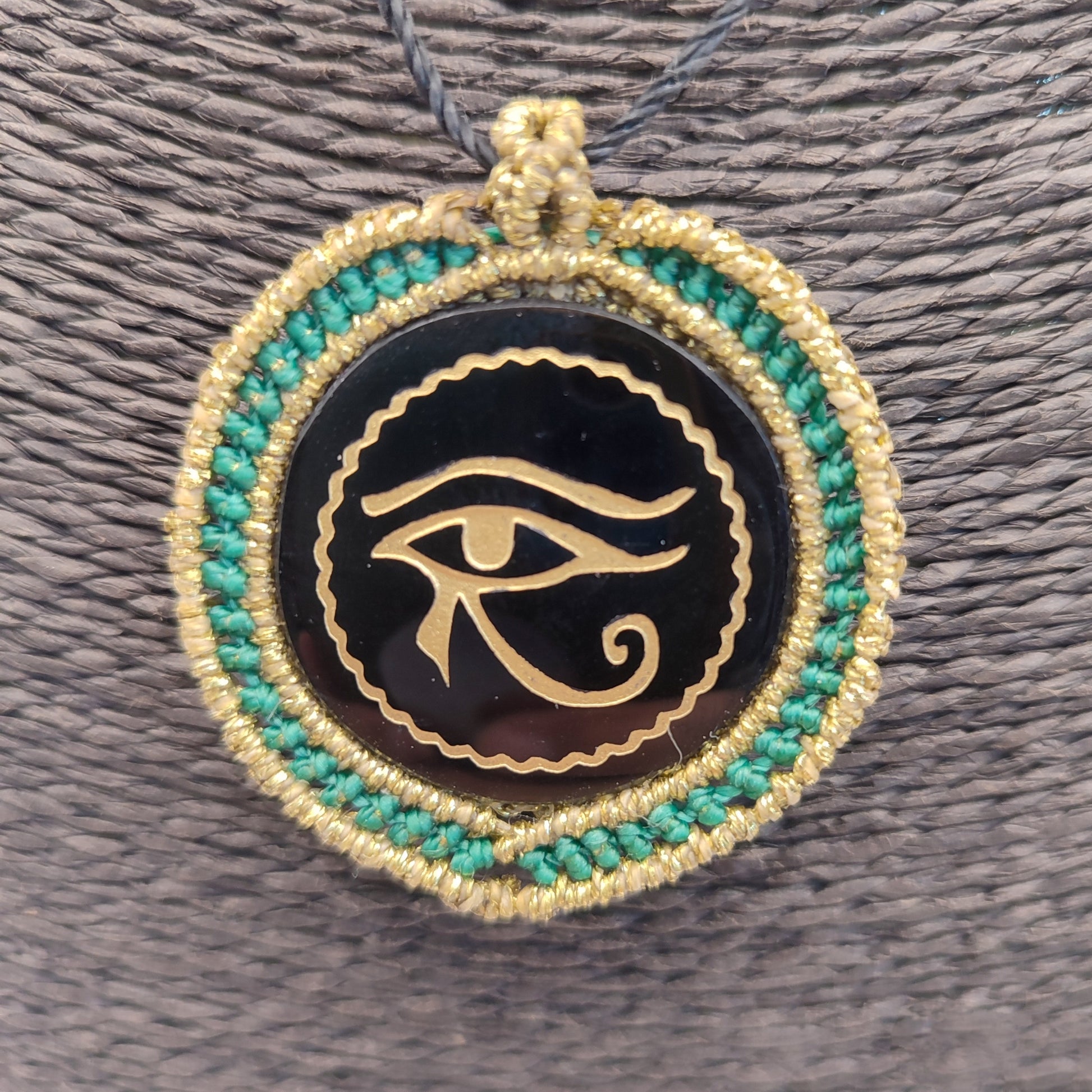 Colgante de obsidiana negra con grabado dorado del Ojo de Horus y macramé turquesa.