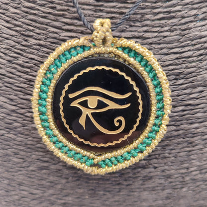 Colgante de obsidiana negra con grabado dorado del Ojo de Horus y macramé turquesa.