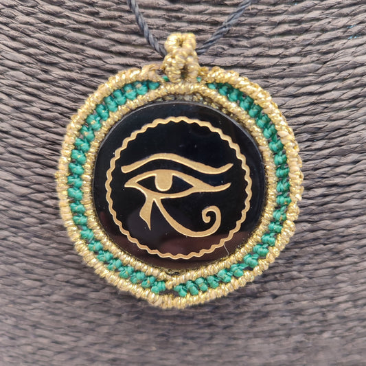 Colgante de obsidiana negra con grabado dorado del Ojo de Horus y macramé turquesa.