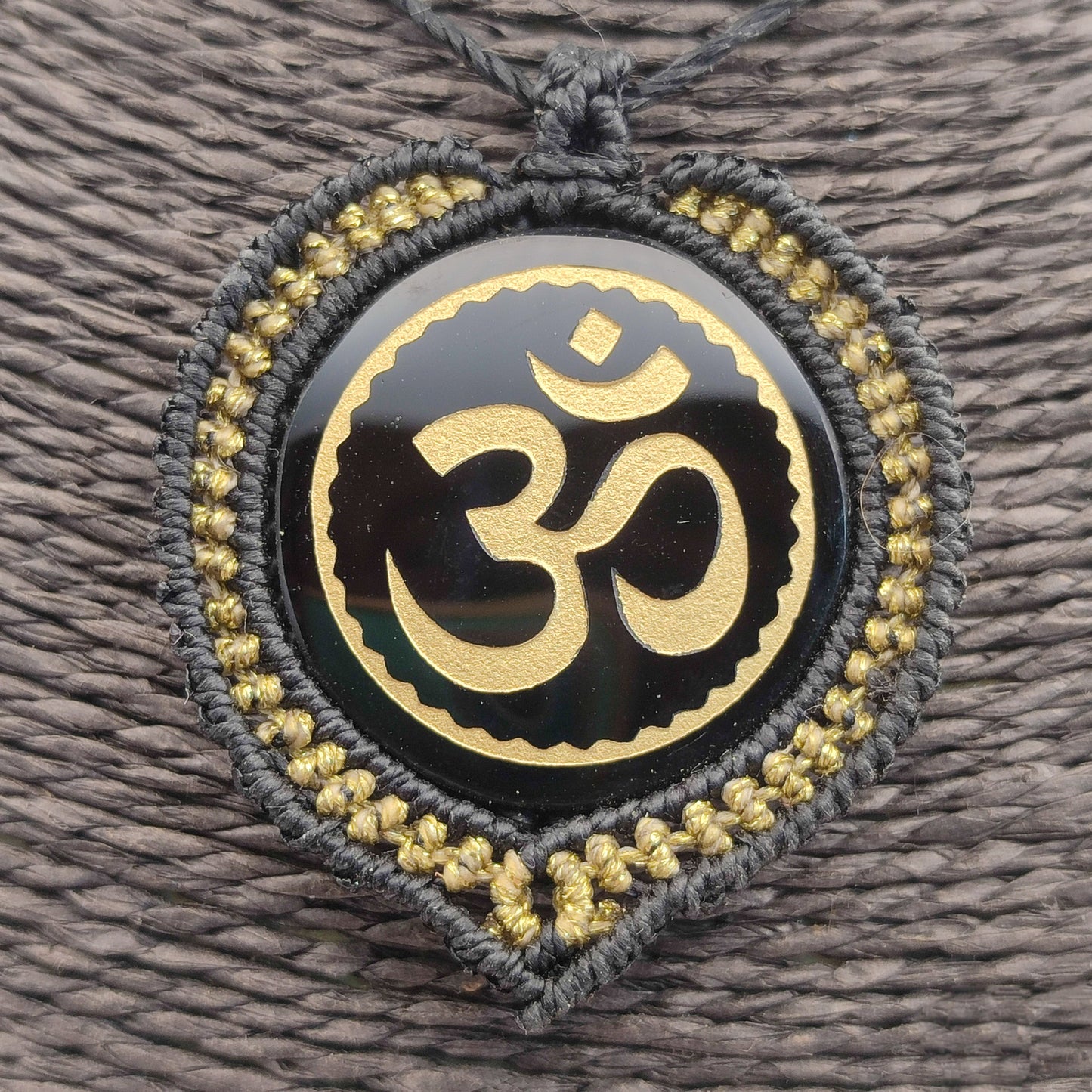 El colgante Om de Teotihuacán en la mano mostrando su brillo y acabado.