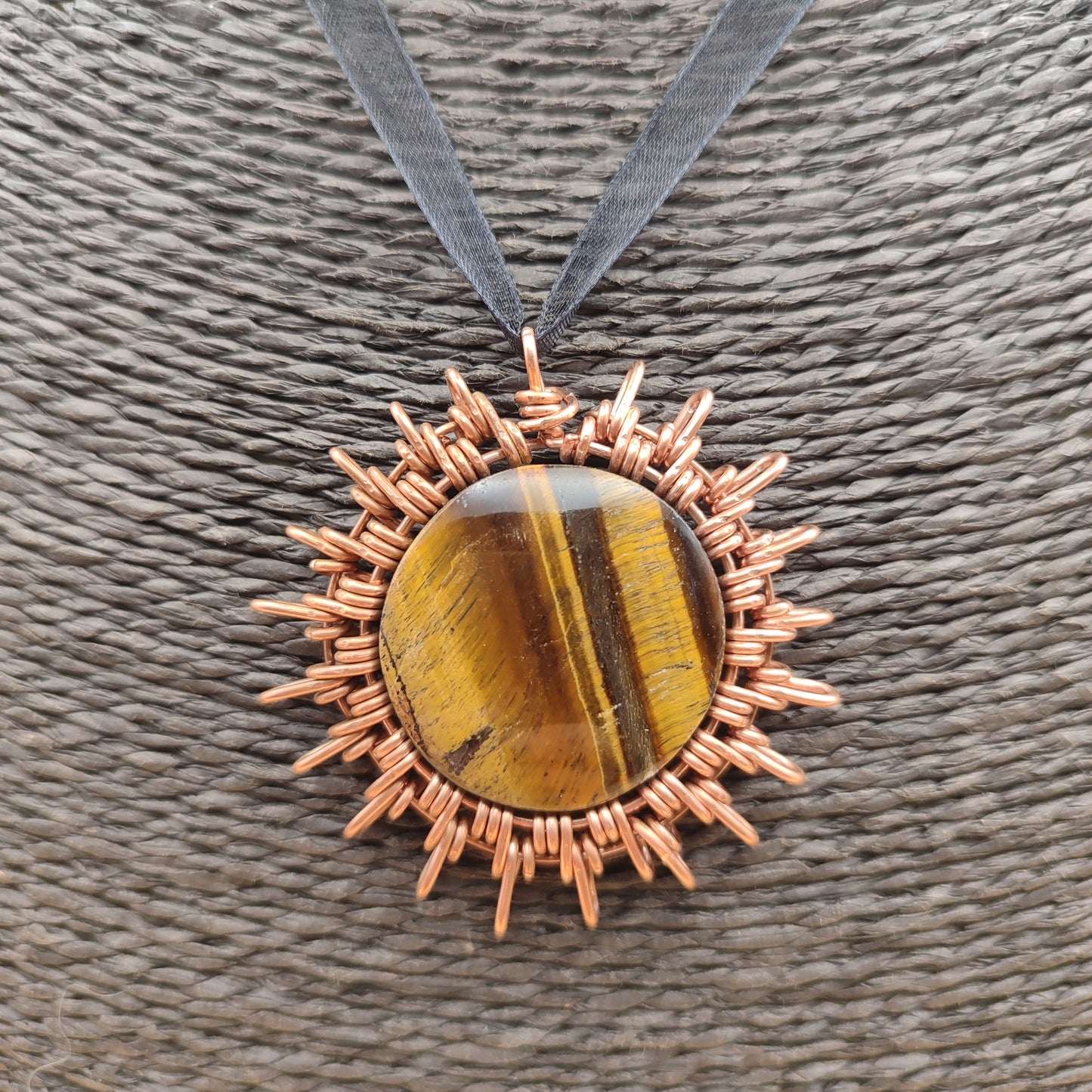 Colgante artesanal de cobre en forma de sol con piedra ojo de tigre natural
