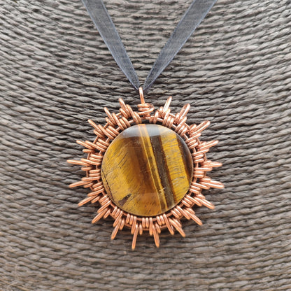 Colgante artesanal de cobre en forma de sol con piedra ojo de tigre natural