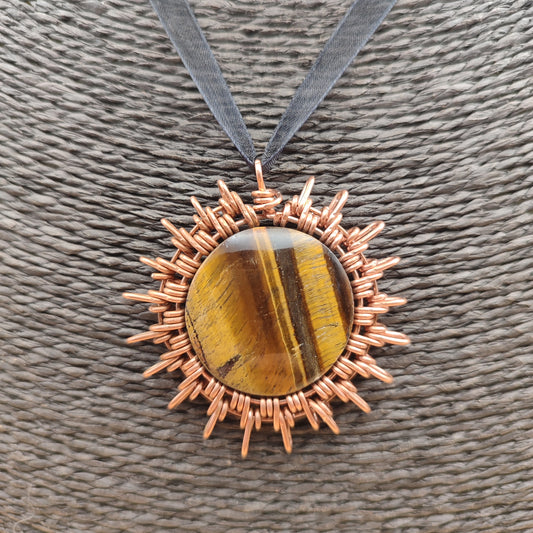 Colgante artesanal de cobre en forma de sol con piedra ojo de tigre natural