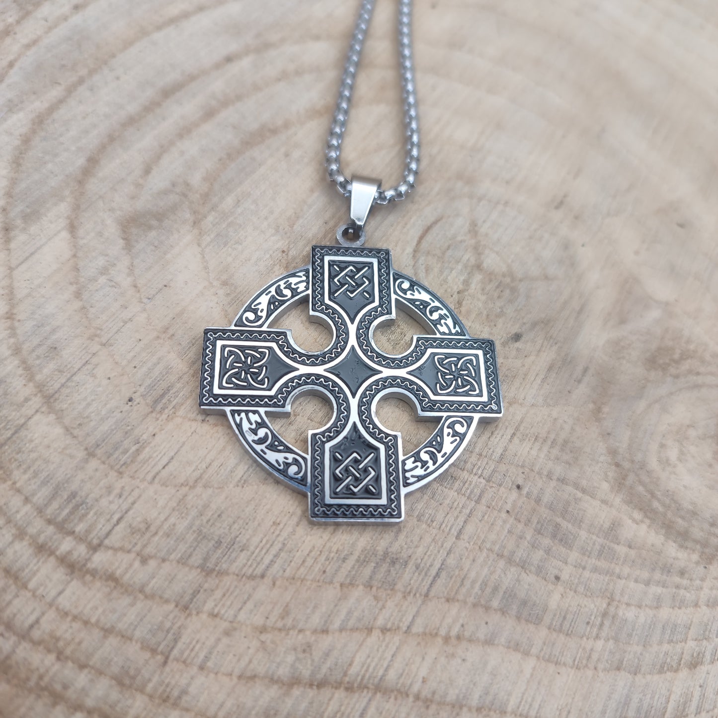 Collar de cruz celta en acero inoxidable estilo vikingo sobre madera