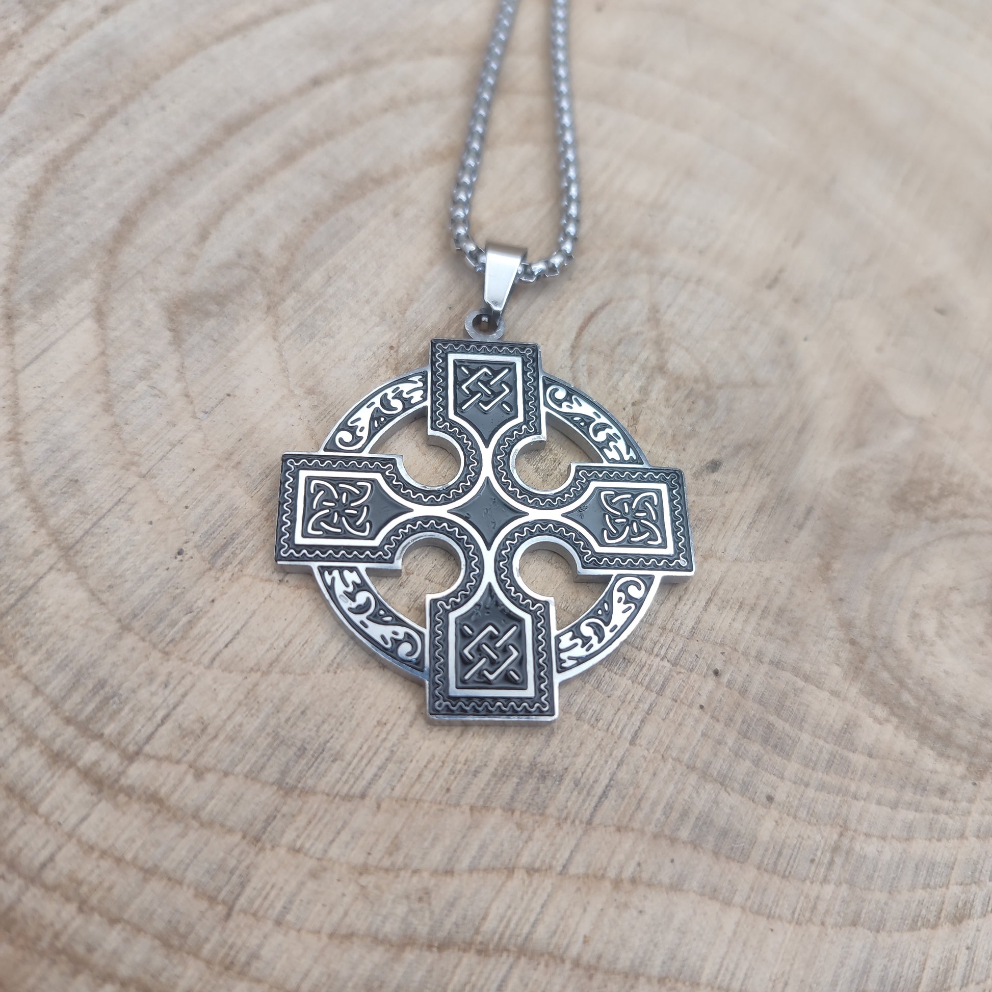 Collar de cruz celta en acero inoxidable estilo vikingo sobre madera