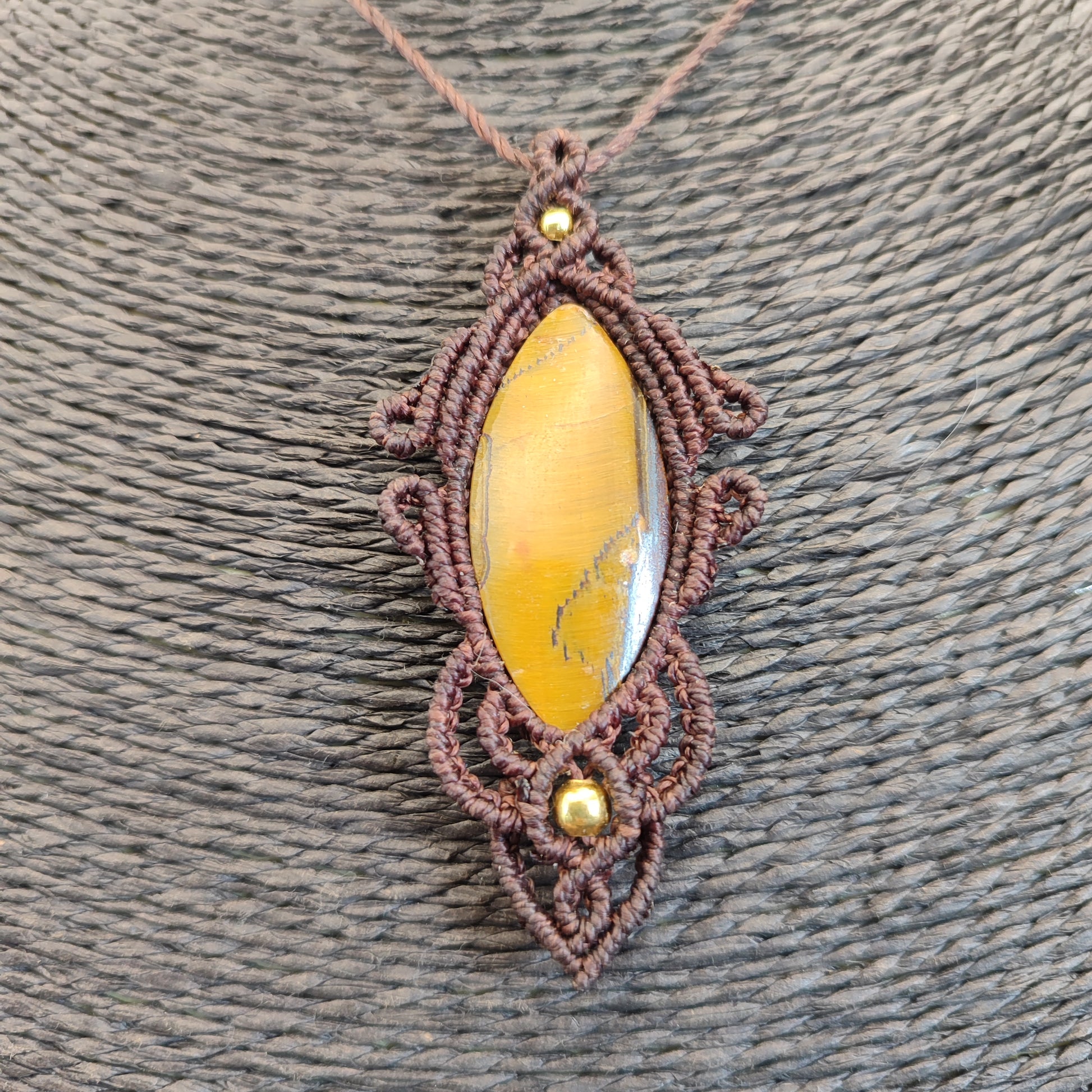 Detalle del tejido artesanal en macramé envolviendo un ojo de tigre