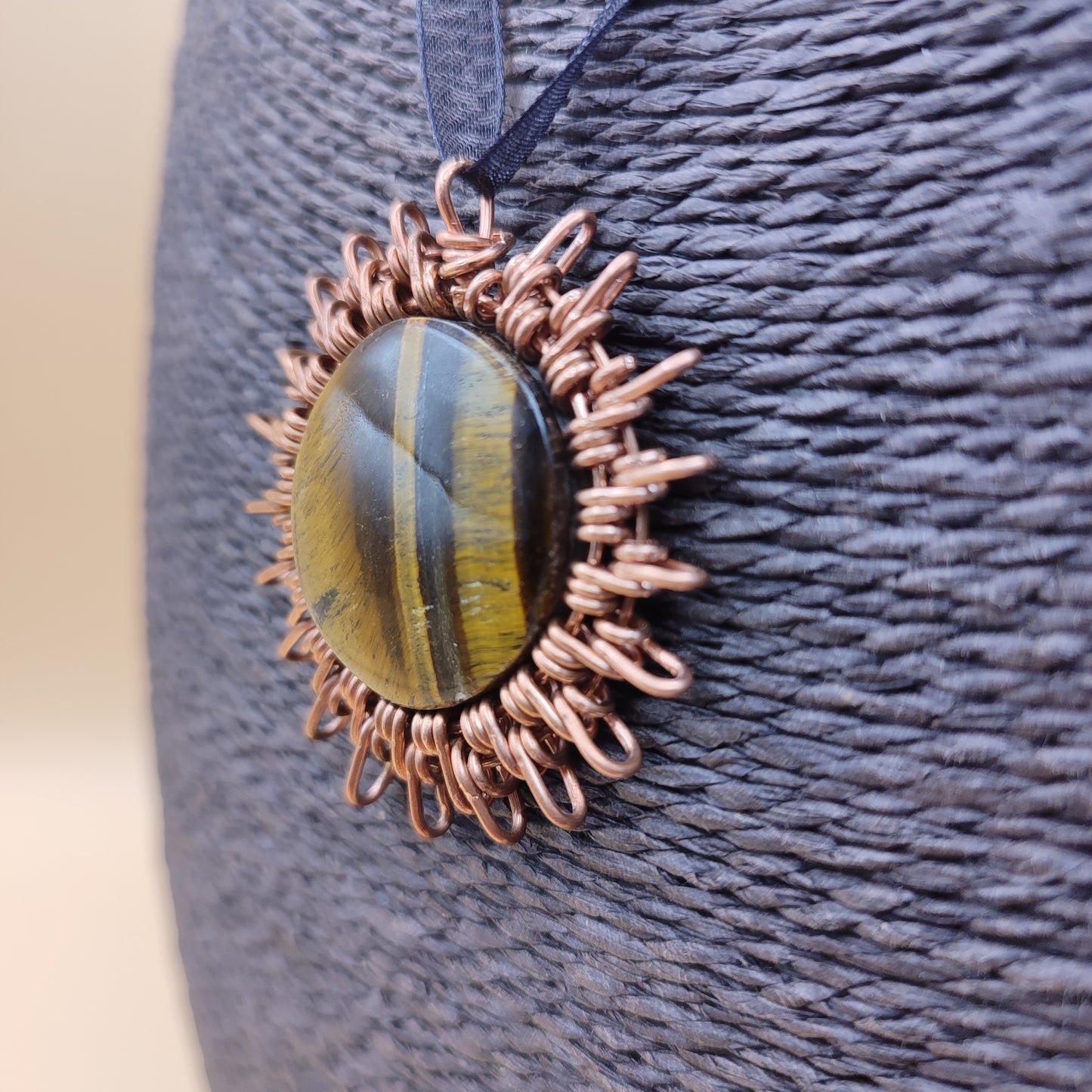Colgante de sol de cobre y ojo de tigre puesto para ver escala y cómo luce