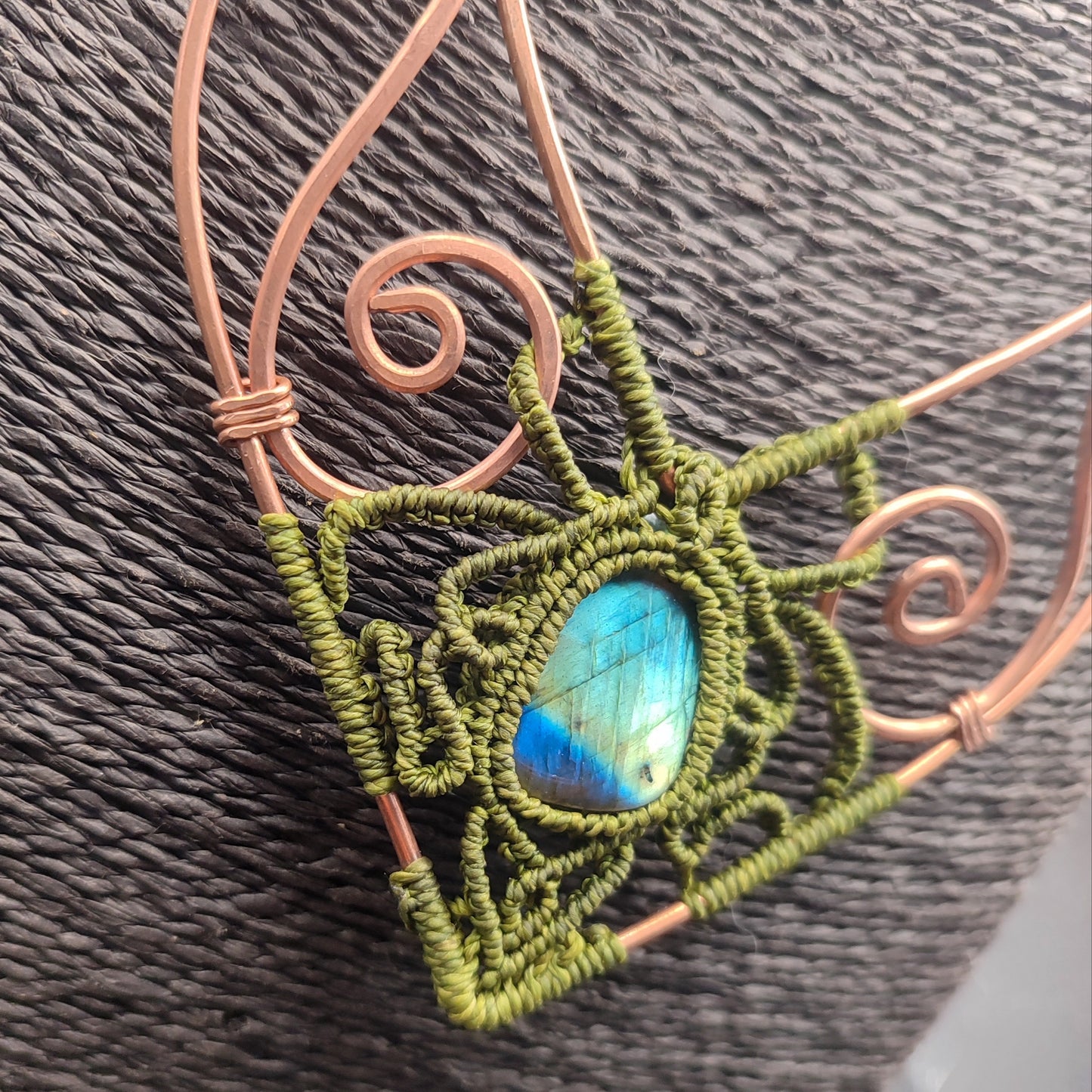 Primer plano del trabajo en cobre y nudos de macramé verde oliva