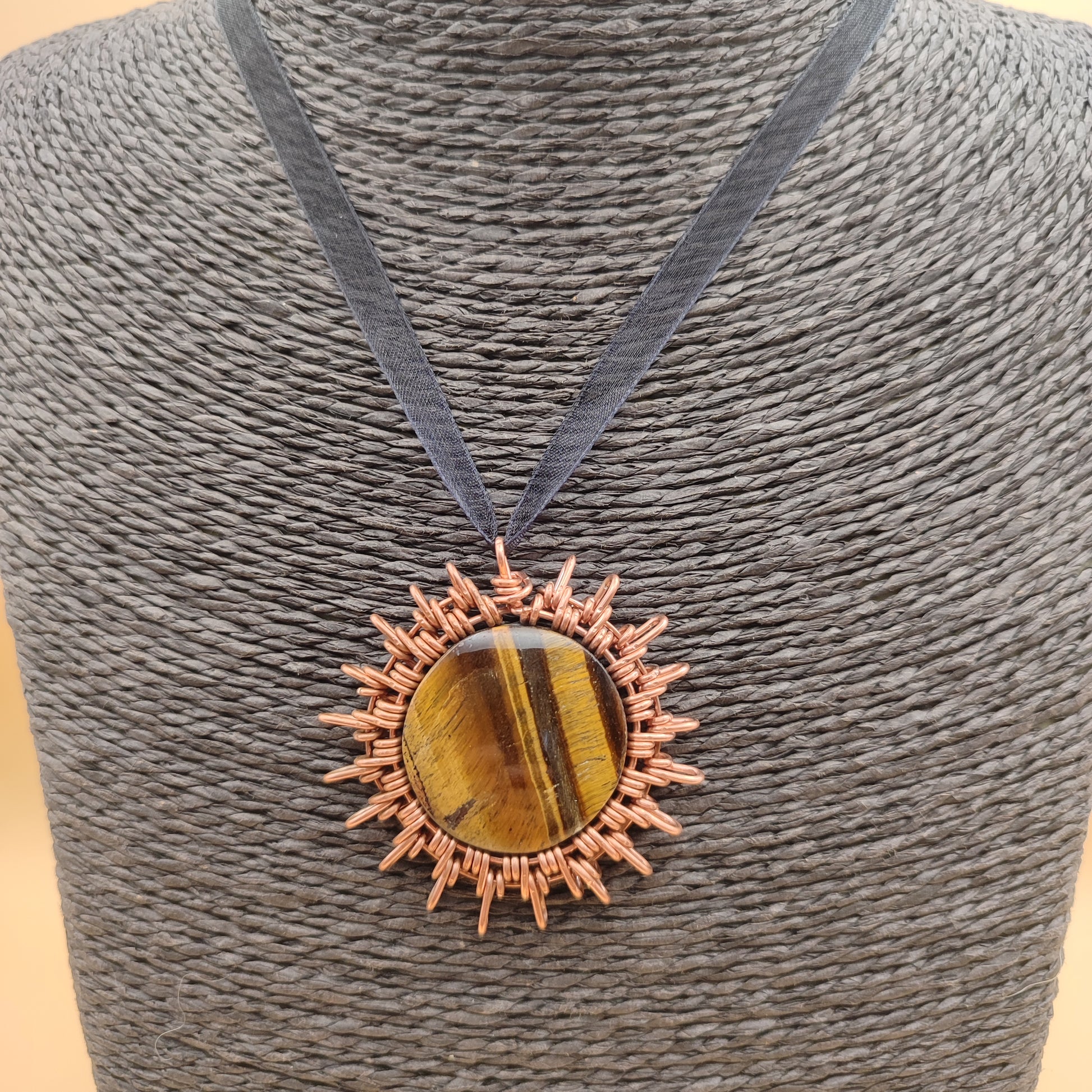 Primer plano de la filigrana de cobre rodeando el cabujón de ojo de tigre.