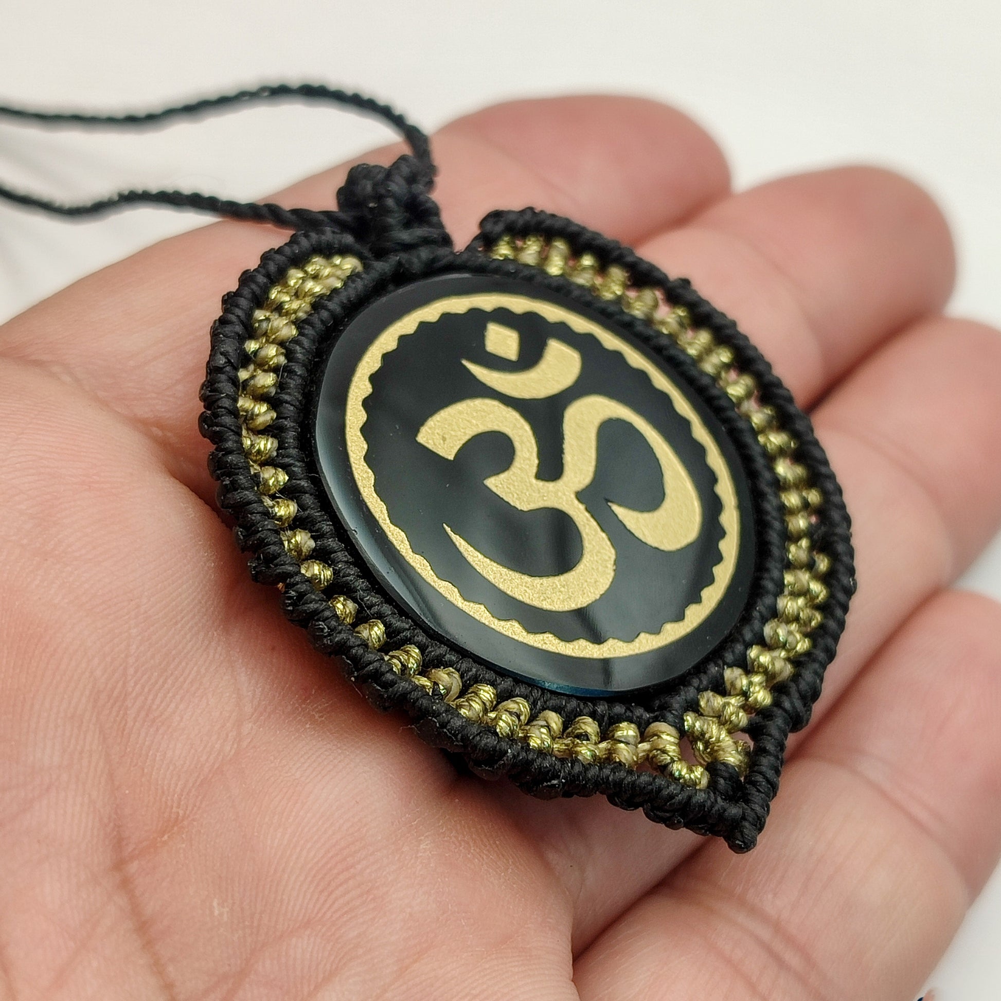 Primer plano del grabado dorado del mantra Om sobre espejo de obsidiana.