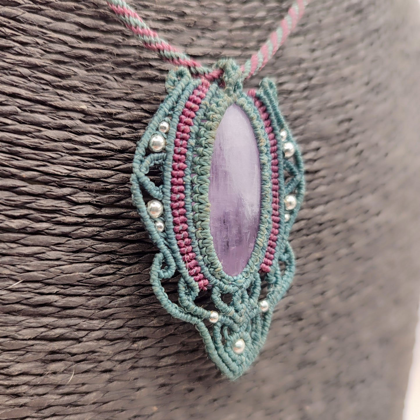 Primer plano del tejido artesanal con hilo de 0,5 mm en colgante de kunzita