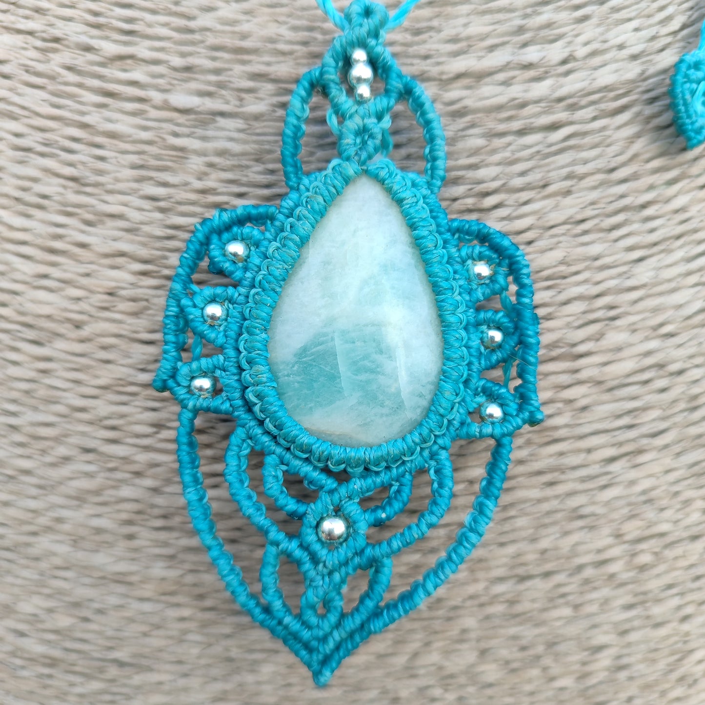 Primer plano de la piedra Larimar y las bolitas de plata entre el tejido