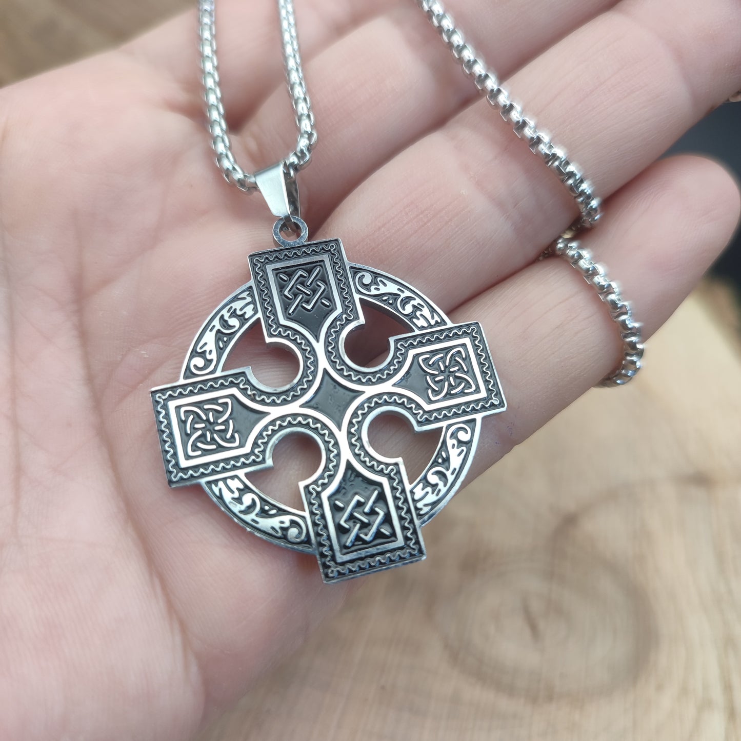 Vista del tamaño real del collar de la cruz de Odín en la mano