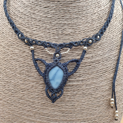 Primer plano del intrincado tejido de micro-macramé rodeando la piedra ópalo azul.