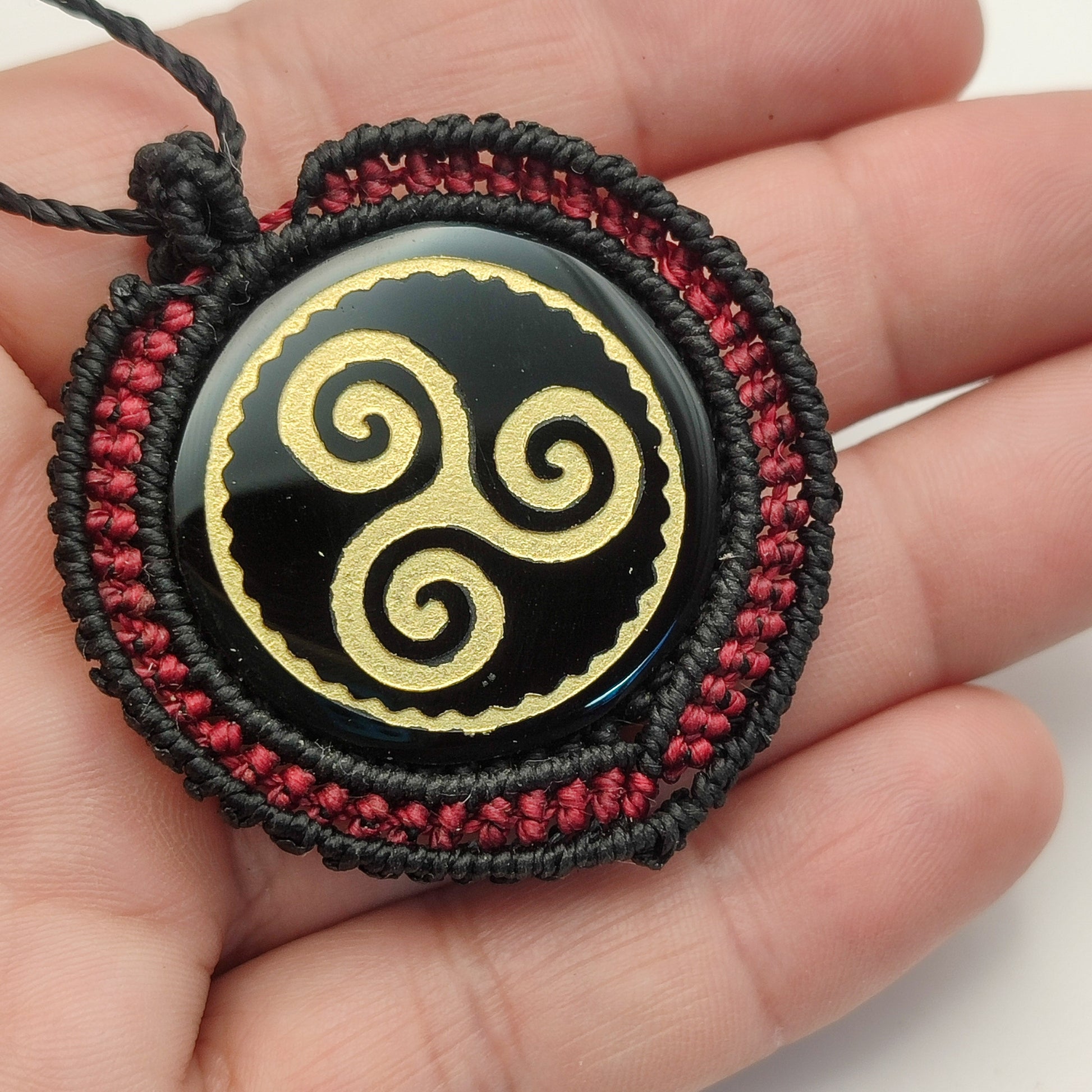 Colgante Trisquel de obsidiana en la mano para mostrar el tamaño y los acabados.