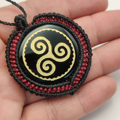 Colgante Trisquel de obsidiana en la mano para mostrar el tamaño y los acabados.