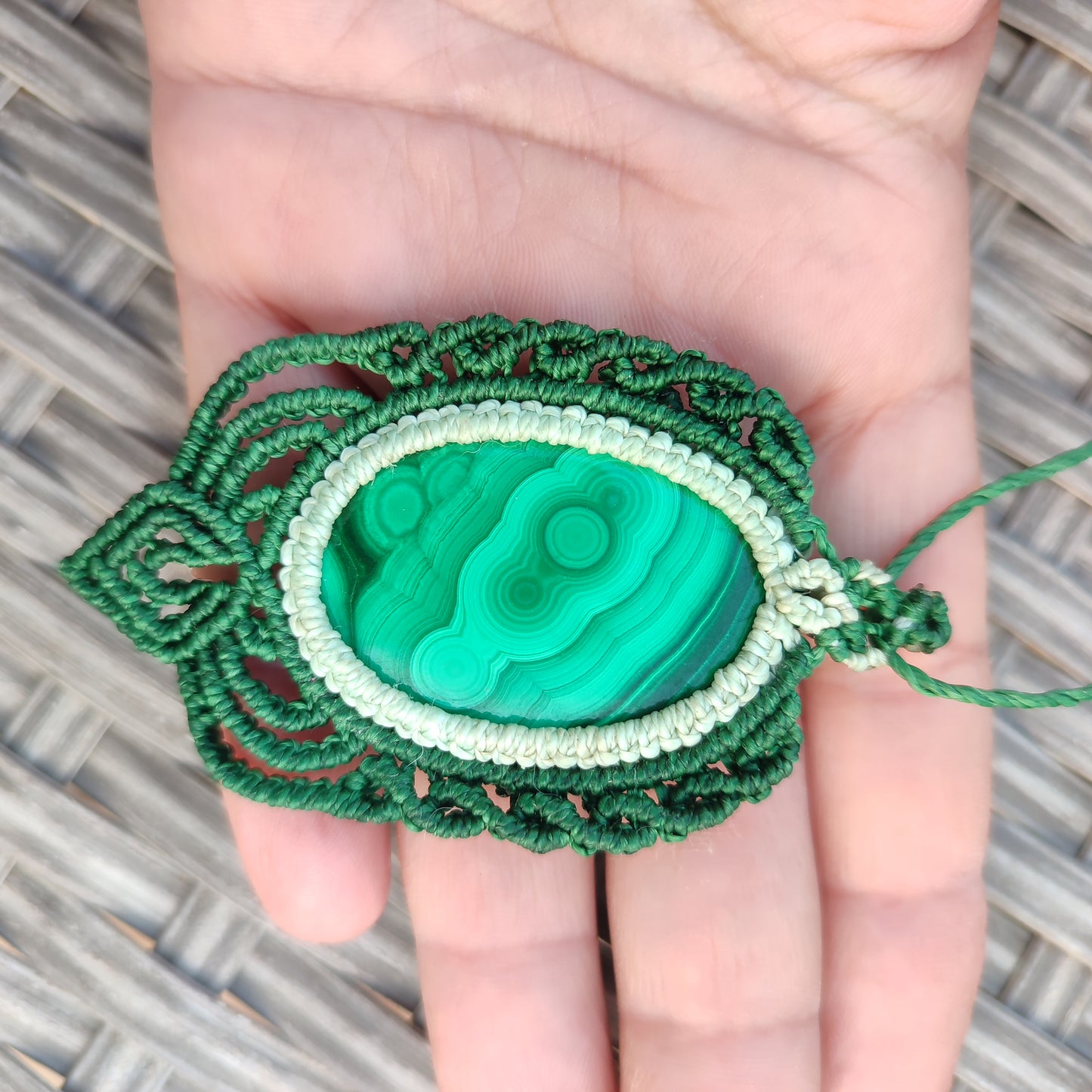 Colgante de malaquita en la mano para mostrar el tamaño real de la gema