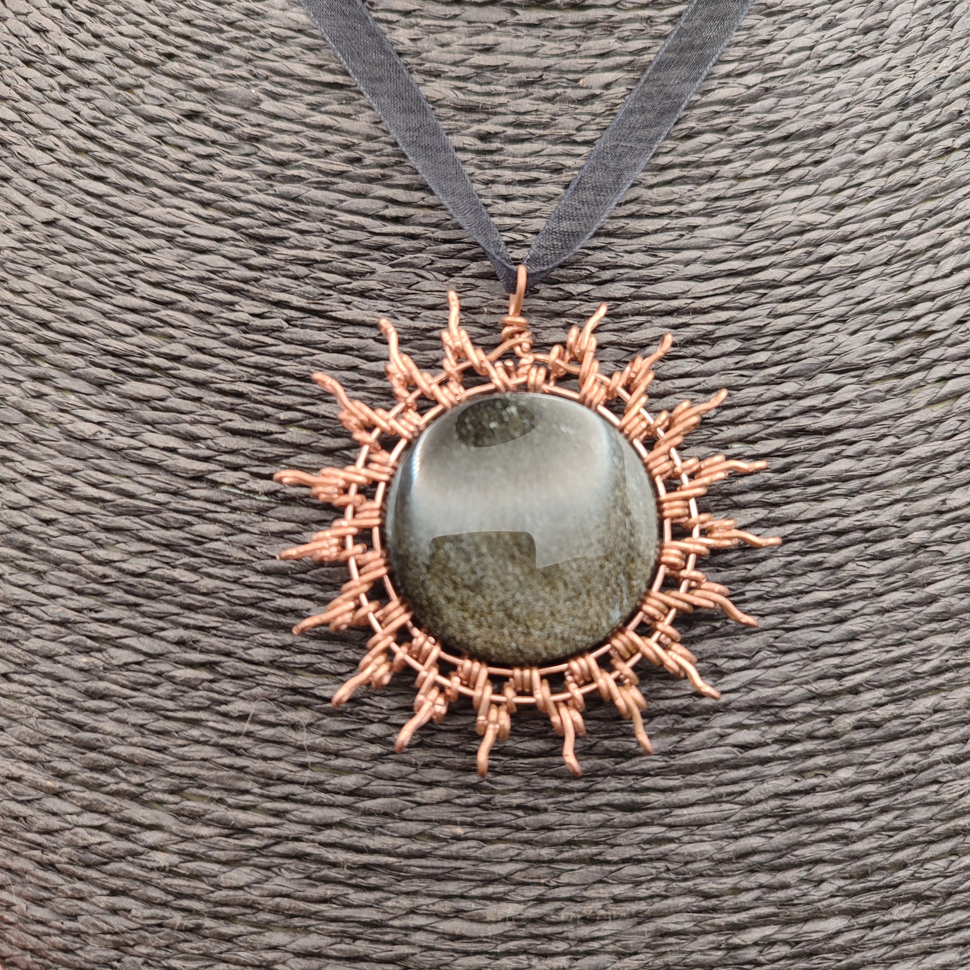 Primer plano de la técnica artesanal de cobre envolviendo la obsidiana.