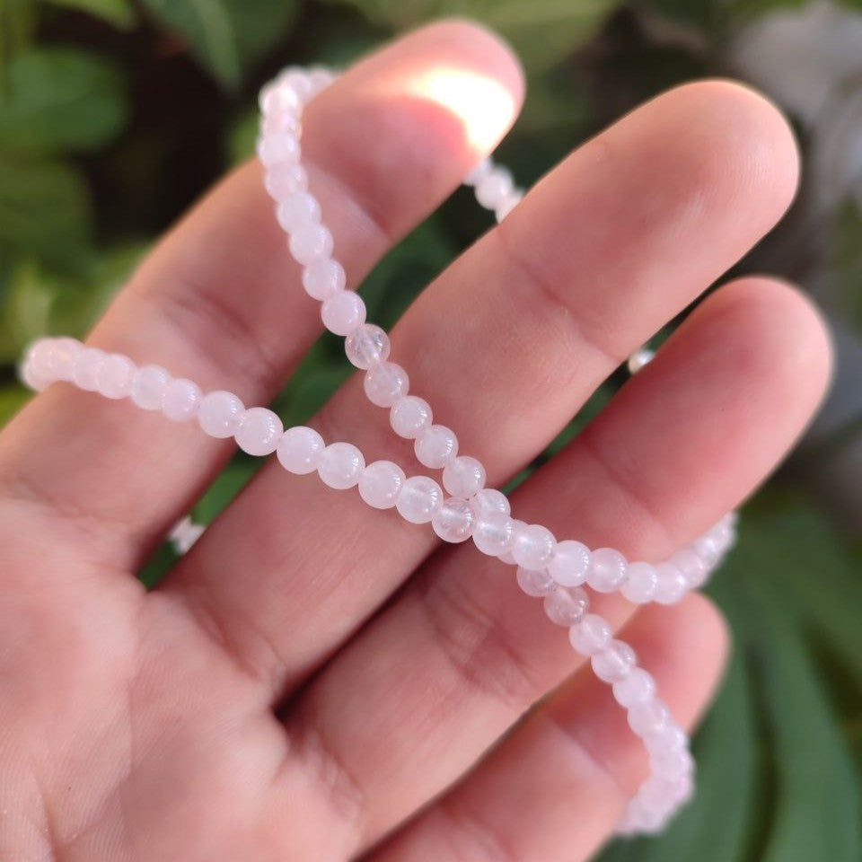 Detalle del collar de cuarzo rosa mostrando su suavidad y flexibilidad