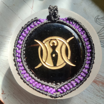 Primer plano del grabado místico de la Triple Diosa sobre el brillo de la obsidiana negra.