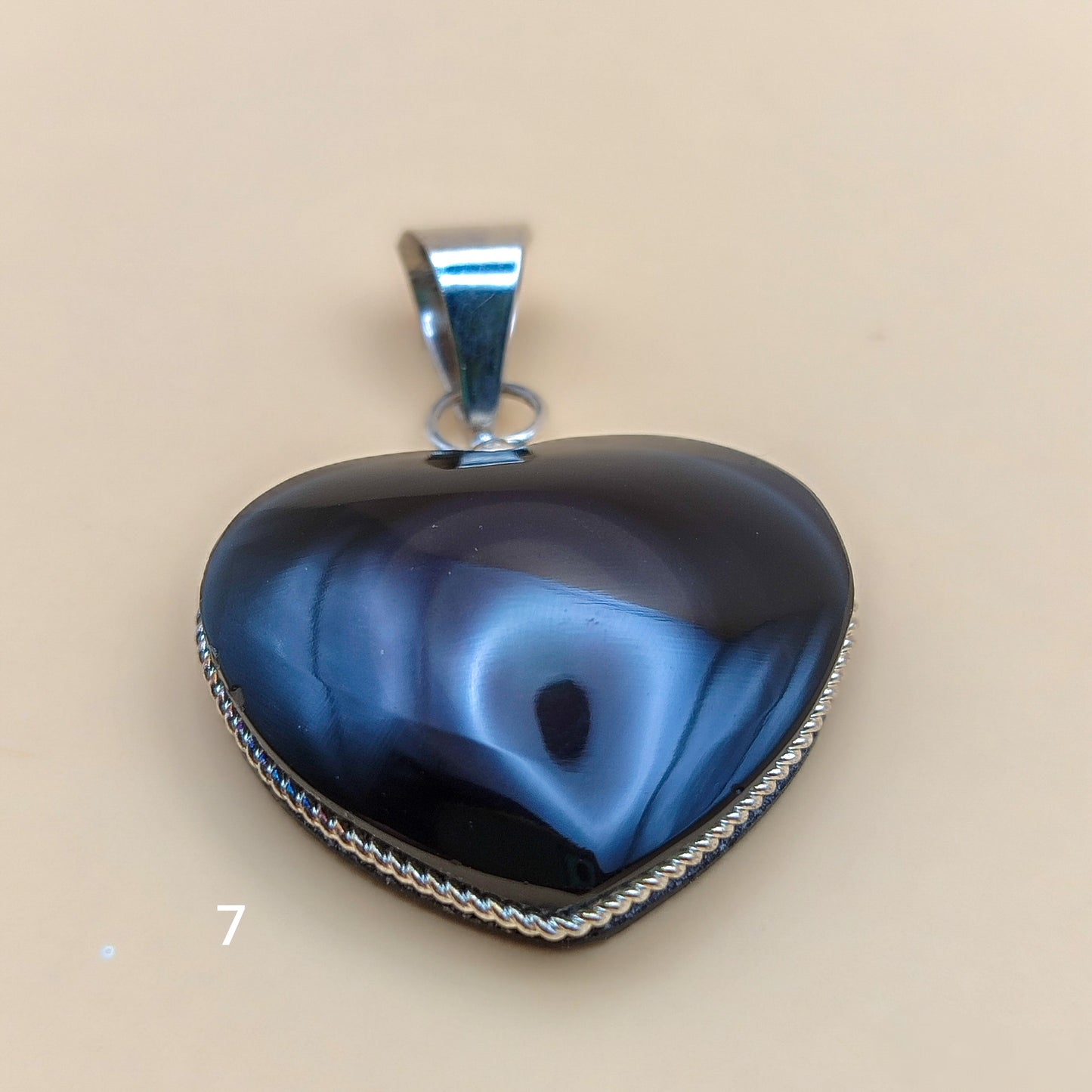 Colgante de corazón con reflejos púrpuras y verdes bajo la luz