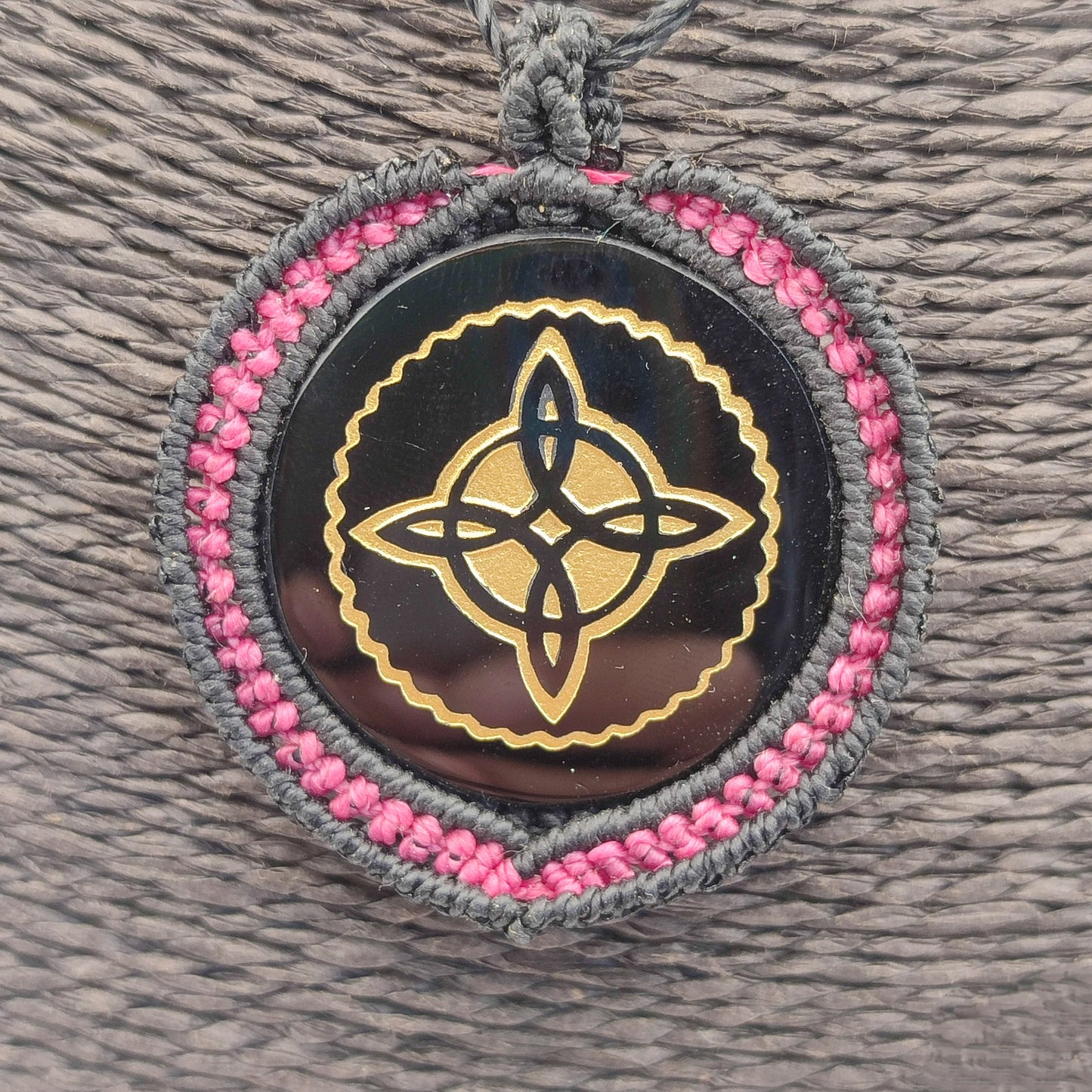 Vista del colgante mostrando el contraste entre el fucsia, el negro y el grabado.