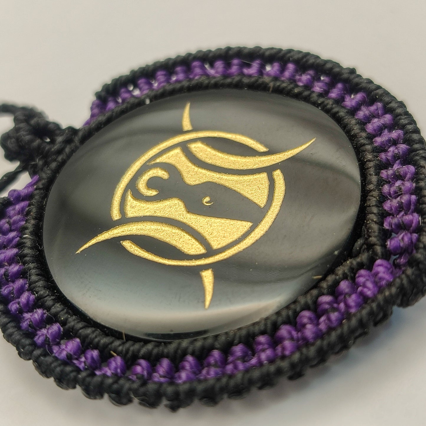 Vista del reflejo del espejo de obsidiana y el contraste con el tejido macramé púrpura.