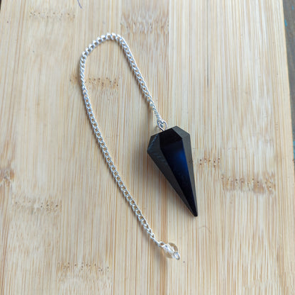 Vista completa de péndulo esotérico de obsidiana negra y cadena estirada para terapias energéticas.