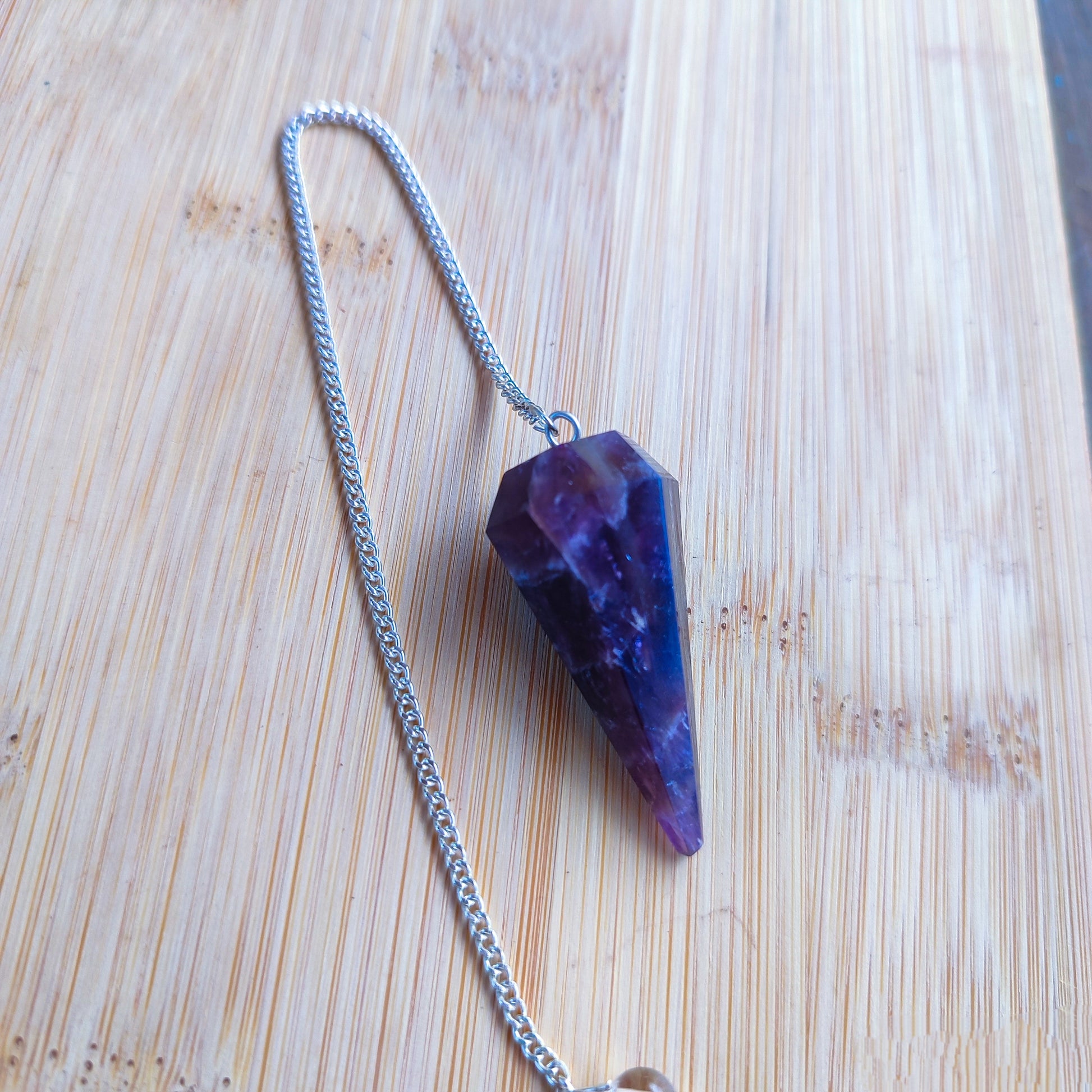 Péndulo de radiestesia facetado en mineral de amatista para sanación y meditación.