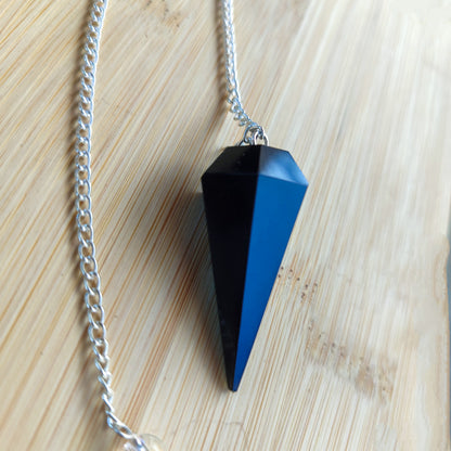 Péndulo de radiestesia de obsidiana negra colgado de su cadena mostrando su equilibrio perfecto.