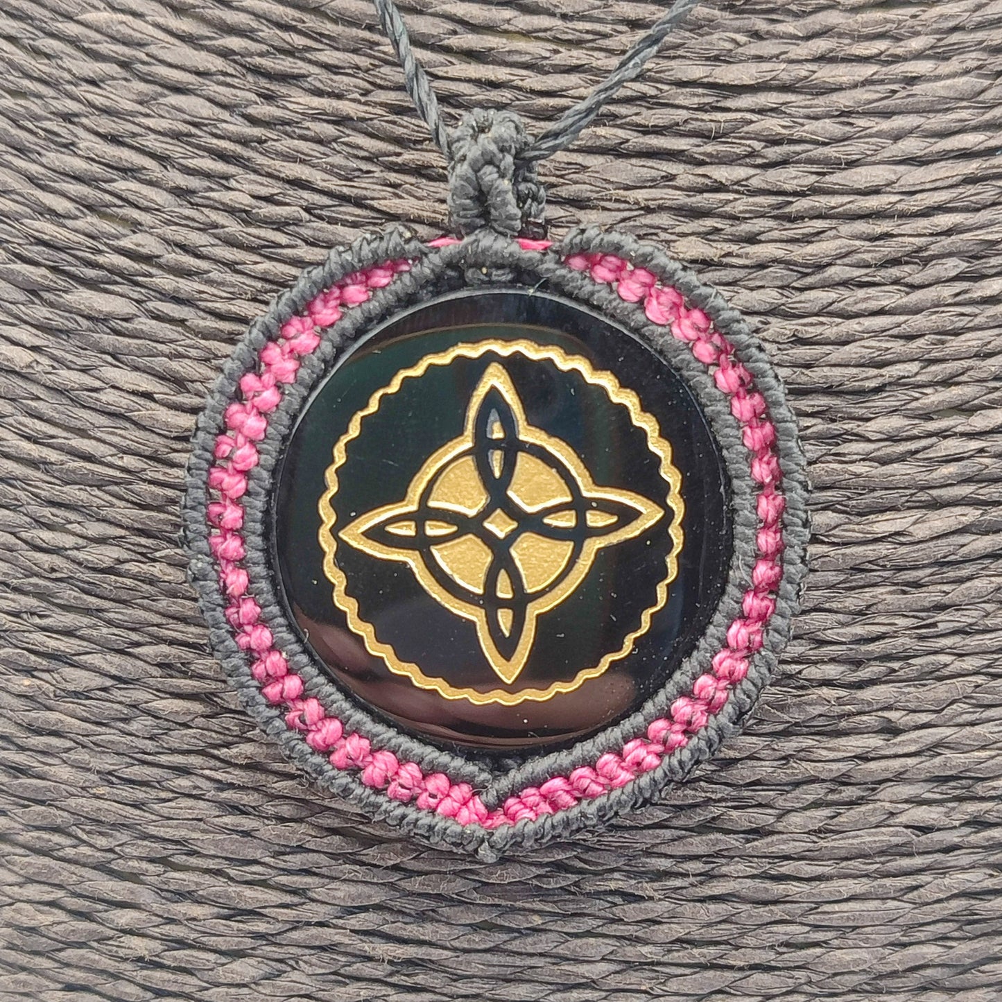 Primer plano del grabado dorado del Nudo de Bruja y el brillo vítreo de la piedra.