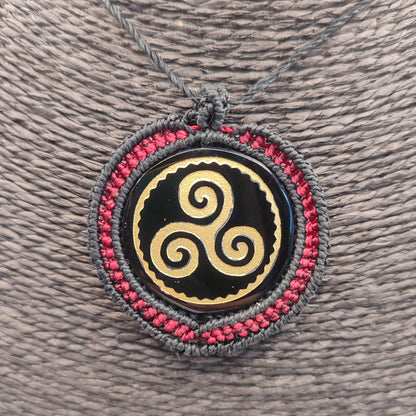 Primer plano del grabado dorado del Trisquel sobre espejo de obsidiana negra